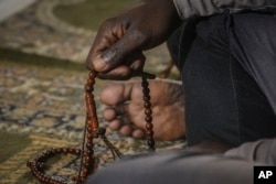 FILE— An African migrant holds a prayer bead during evening prayers, March 15, 2024, at Bronx's Masjid Ansaru-Deen mosque in New York.