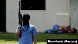 Seorang teroris tiruan memegang senapan di dekat "warga sipil yang ditahan" dalam latihan anti-teror di markas pasukan khusus polisi di Depok, Jawa Barat, 9 Maret 2010. (Foto: REUTERS/Beawiharta)