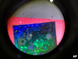 FILE - A Chinese microchip is seen through a microscope set up at the booth for the state-controlled Tsinghua Unigroup project which is driving China's semiconductor ambitions during the 21st China Beijing International High-tech Expo in Beijing.