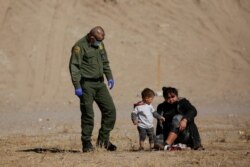 A migrant puts on her shoes after crossing the Rio Bravo river to turn herself in to a U.S. Border Patrol agent to request for asylum in El Paso, Texas, as seen from Ciudad Juarez, Mexico, Feb. 8, 2021.