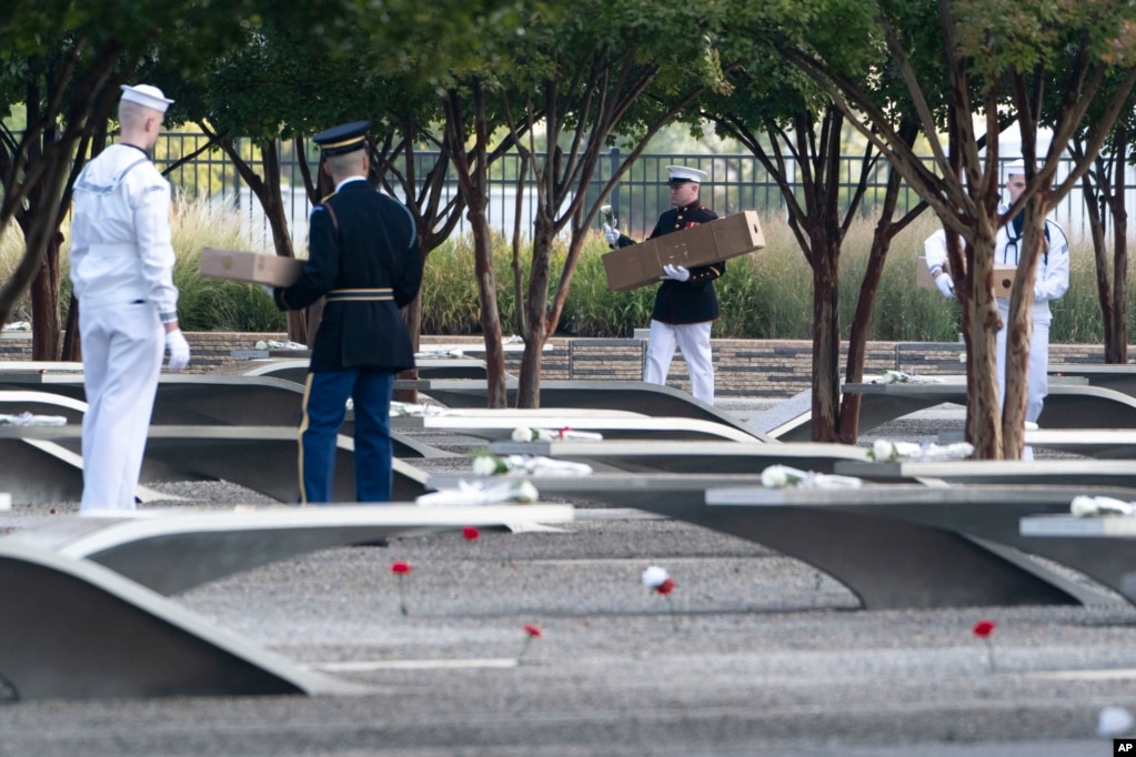 En el Pentágono Memorial, miembros de la guardia instalan flores y banderas en los bancos conmemorativos. 