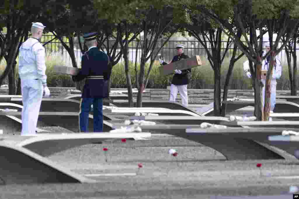 En el Pentágono Memorial, miembros de la guardia instalan flores y banderas en los bancos conmemorativos.&nbsp;