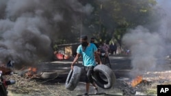 Un residente lleva neumáticos para colocarlos en una barricada en llamas para disuadir a los pandilleros de entrar a su vecindario, en Puerto Príncipe, Haití, el martes 19 de noviembre de 2024. 