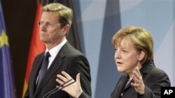 German Chancellor Angela Merkel, right, and Vice Chancellor Guido Westerwelle, left, address the media during a joint news conference Berlin, Germany, March 12, 2011