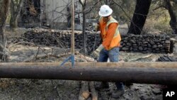 FILE - In this Oct. 18, 2017, photo, a Pacific Gas & Electric worker replaces power poles destroyed by wildfires in Glen Ellen, Calif. The National Weather Service has issued warnings for increased fire risk across a swath of Northern California on Oct. 14-15, 2018.