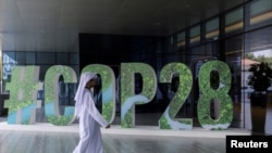 FILE—A person walks past a "#COP28" sign during The Changemaker Majlis, a one-day CEO-level thought leadership workshop focused on climate action, in Abu Dhabi, United Arab Emirates, October 1, 2023.