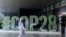 FILE—A person walks past a "#COP28" sign during The Changemaker Majlis, a one-day CEO-level thought leadership workshop focused on climate action, in Abu Dhabi, United Arab Emirates, October 1, 2023.
