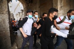 Palestinians evacuate a wounded protester during clashes with Israeli security forces at the Lions Gate in Jerusalem's Old City, May 10, 2021.