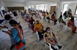 People sit in a waiting area to receive a dose of COVISHIELD, a coronavirus disease (COVID-19) vaccine manufactured by Serum Institute of India, at a vaccination center in Ahmedabad, India, Apr. 2, 2021.