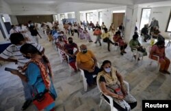 People sit in a waiting area to receive a dose of COVISHIELD, a coronavirus disease (COVID-19) vaccine manufactured by Serum Institute of India, at a vaccination center in Ahmedabad, India, Apr. 2, 2021.