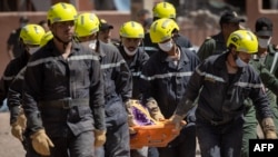 Moroccan rescuers carry a body out of the rubble in Talat N'Yacoub village of al-Haouz province in earthquake-hit Morocco on September 11, 2023.