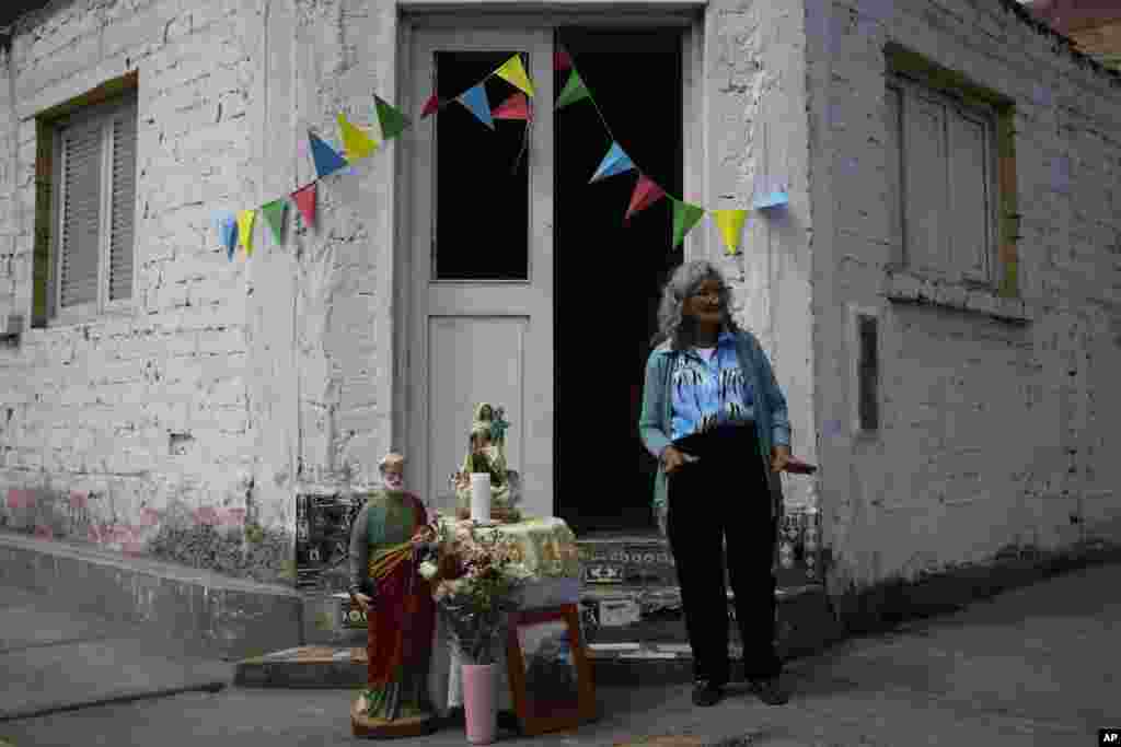 María Huapaya, de 80 años, devota de San Pedro, santo patrón católico de los pescadores, espera en la puerta de su casa el paso de la procesión del santo en Pucusana, Perú, el jueves 29 de junio de 2023.&nbsp;