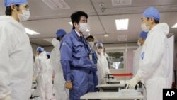 Perdana Menteri baru Jepang, Shinzo Abe (tengah), berbincang dengan pekerja di Pusat Operasi Darurat Tokyo Electric Power Co.(TEPCO) di PLTN Okuma, Fukushima, Jepang (29/12).