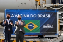 Brazil's Sao Paulo state Governor Joao Doria and state Health Secretary Jean Gorinchteyn hold boxes of the China's Sinovac vaccines against the coronavirus disease near a refrigerated container at Sao Paulo International Airport, Dec. 30, 2020.