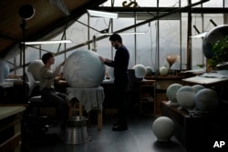 Artists make a globe at a studio in London, Tuesday, Feb. 27, 2024. The most ornate can cost six figures. (AP Photo/Kin Cheung)