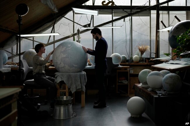 Artists make a globe at a studio in London, Tuesday, Feb. 27, 2024. The most ornate can cost six figures. (AP Photo/Kin Cheung)