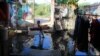 A girl stands in a flood of water, holding a sleeping mat, in front of Khoeun Sovat’s house in Boeung Kak community in Phnom Penh, Cambodia, Nov. 13, 2014. (Nov Povleakhena/VOA Khmer)