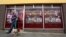Kevin Maguire walks his dog past a vacant shop, with graphics pasted to the outside to make it look like a working butcher's shop, in the village of Belcoo, Northern Ireland, June 3, 2013. 
