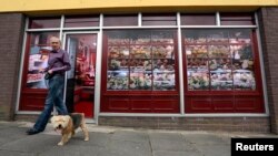 Kevin Maguire walks his dog past a vacant shop, with graphics pasted to the outside to make it look like a working butcher's shop, in the village of Belcoo, Northern Ireland, June 3, 2013. 