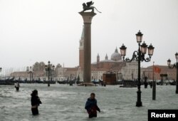 Ljudi hodaju potopljenim Trgom svetog Marka, tokom perioda visokih voda u Veneciji, Italija, 29. oktobra 2018.