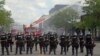 Minnesota state troopers provide protection as firefighters battle a fire, May 29, 2020, after another night of protests, fires and looting over the arrest of George Floyd who died in police custody Monday night in Minneapolis.