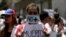 A woman wears a mask and a banner that read "No more deaths" as she takes part in a rally of workers of the health sector against President Nicolas Maduro's government in Caracas, Venezuela, May 17, 2017. 