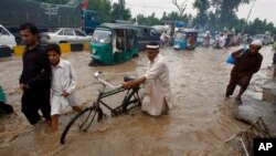 Kendaraan dan warga Peshawar, Pakistan melintasi jalanan yang banjir akibat hujan lebat yang mengguyur wilayah ini, Sabtu (3/8). Hujan lebat selama tiga hari belakangan ini di berbagai wilayah di Pakistan dilaporkan telah menewaskan sedikitnya 53 orang.