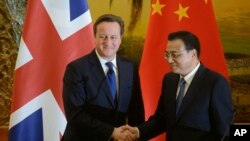 英国首相卡梅伦（左）和中国总理李克强12月2日在人民大会堂举行联合新闻发布会时握手。