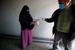 Sukarelawan Turki dari layanan pengiriman makanan "Iftar to go", Ural Hasan, 55, membagikan makanan kepada seorang perempuan Muslim Bangladesh pencari suaka untuk dirinya dan keluarganya, termasuk dua anak kecil, selama Ramadan di tengah pandemi COVID-19 di Wuppertal, Jerman. (Foto: dok).