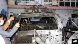 Afghan journalists take a photos of destroyed vehicle inside a house after US drone strike in Kabul, Aug. 29, 2021. 