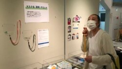 In this photo provided by curator Makoto Mochida of The Historical Museum of Urahoro, Shoko Maede, a nursery-school cook, looks at a display of masks at the museum, in Hokkaido, northern Japan on Aug. 14, 2020. (Makoto Mochida/The Historical Museum of Ura