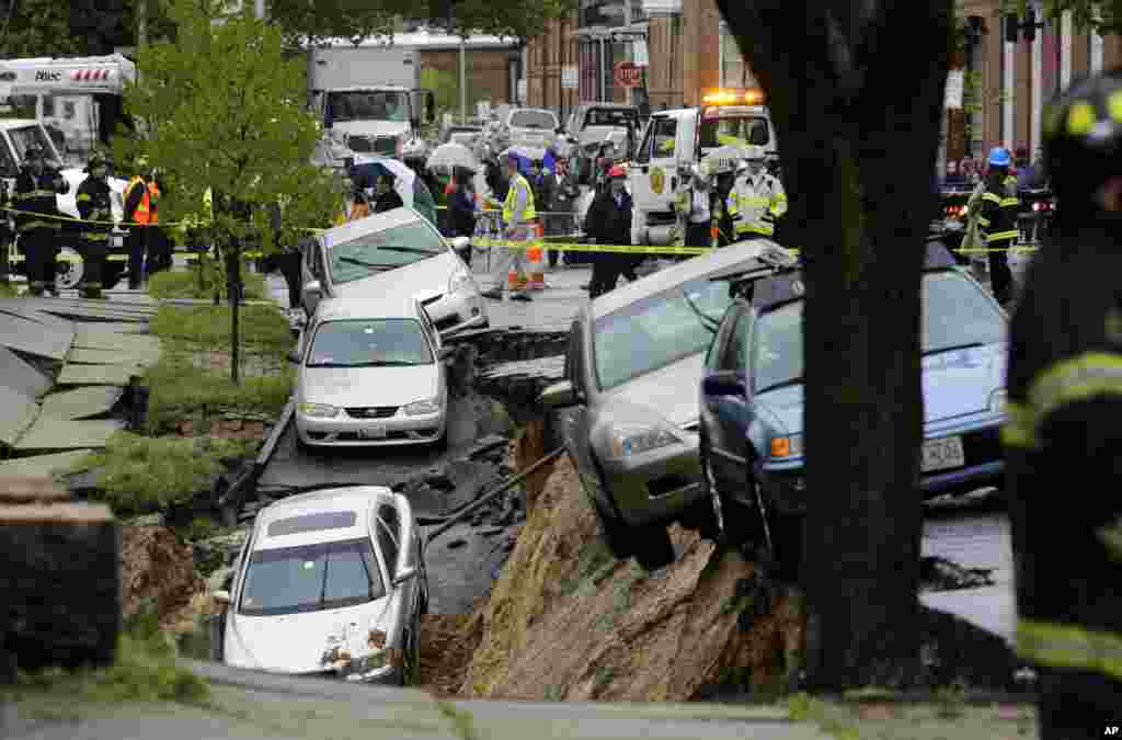 Cars sit on the edge of a sinkhole in the Charles Village neighborhood of Baltimore, USA, April 30, 2014, as heavy rain moves through the region. Road closures have been reported due to flooding, downed trees and electrical lines elsewhere in the Mid-Atlantic.