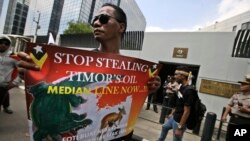 FILE - In this March 24, 2016 file photo, a protester holds a poster during a rally outside the Australian Embassy in Jakarta, Indonesia, as dozens of people show their support to East Timor in the dispute over oil and gas revenue-sharing between the two 