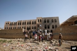 People gather at a school damaged by Saudi-led airstrikes in Sanaa, Yemen,, July 20, 2015.