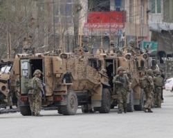 FILE - NATO soldiers inspect near the site of an attack in Kabul, Afghanistan, March 25, 2020.
