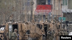 FILE - NATO soldiers inspect near the site of an attack in Kabul, Afghanistan, March 25, 2020.