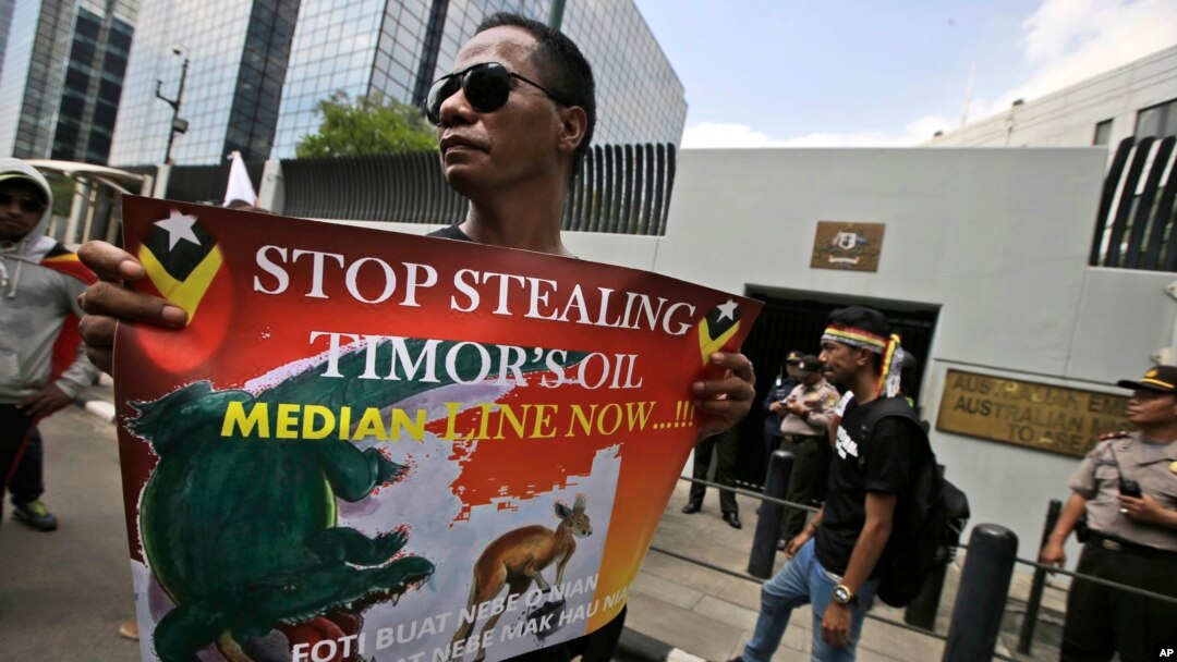 FILE - In this March 24, 2016 file photo, a protester holds a poster during a rally outside the Australian Embassy in Jakarta, Indonesia, as dozens of people show their support to East Timor in the dispute over oil and gas revenue-sharing between the two 