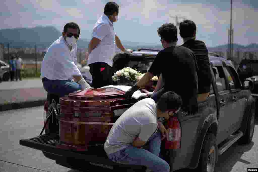 Personas esperan al lado de un ataúd en una camioneta alineada afuera de un cementerio, después que el gobierno informó el jueves que estaba construyendo un &quot;campamento especial&quot; en Guayaquil para los fallecidos por coronavirus.