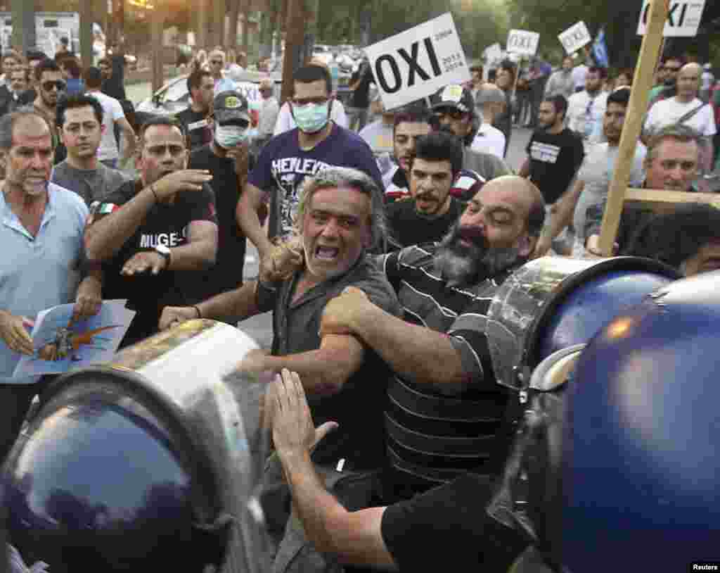 Demonstran bentrok dengan polisi di luar gedung parlemen di Nicosia, ibukota Siprus Yunani, setelah anggota parlemen menyetujui program dana talangan Uni Eropa.