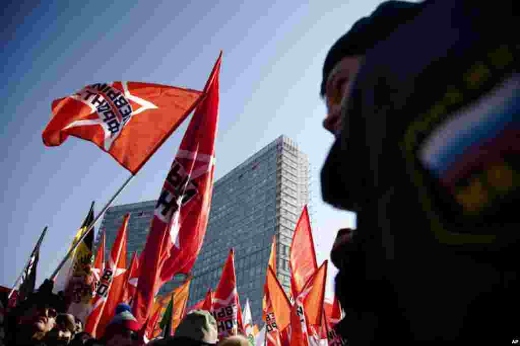 Protesters wave flags at a rally for fair elections in Moscow while a police officer stands by. (VOA Photo - Yuli Weeks)