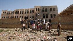 People gather at a school damaged by Saudi-led airstrikes in Sanaa, Yemen, July 20, 2015. 