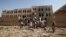 People gather at a school damaged by Saudi-led airstrikes in Sanaa, Yemen, July 20, 2015. 