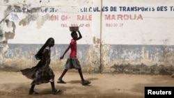 FILE - Girls walk on a road in Maroua, Cameroon, March 17, 2016. Menstruation remains stigmatized in Cameroon and the cost of sanitary pads out of reach for many woman and girls.