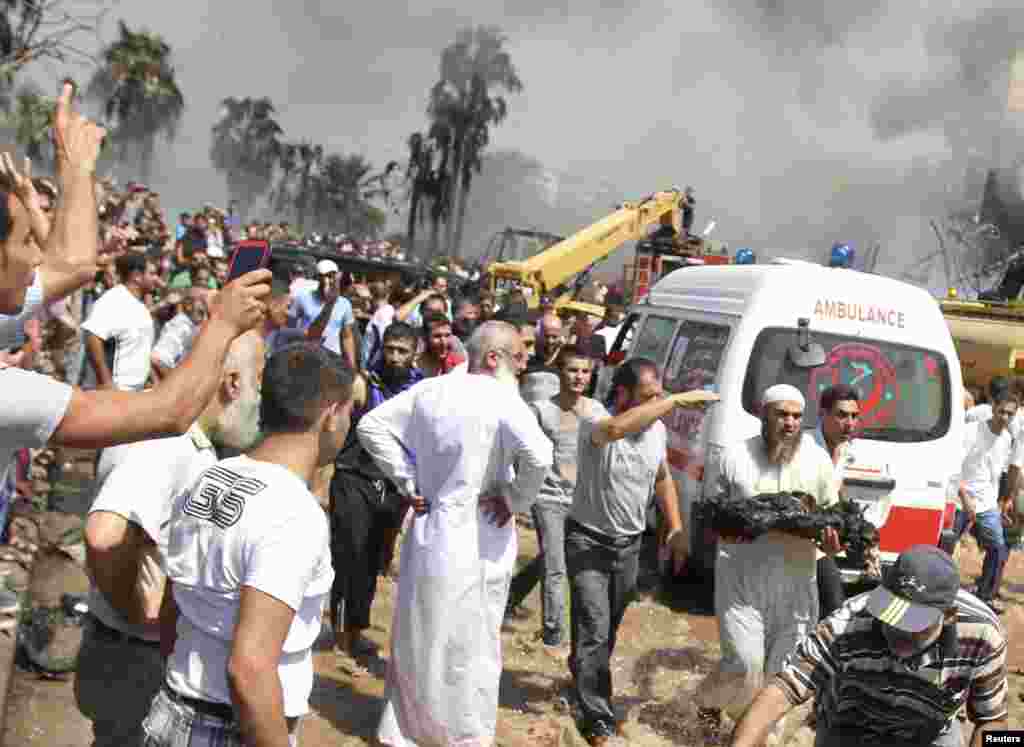 Sunni Sheikh runs as he holds a burned body outside one of two mosques hit by explosions, Tripoli, Lebanon, August 23, 2013.