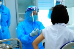 FILE - A health worker injects a doctor with a dose of AstraZeneca COVID-19 vaccine at Hospital for Tropical Diseases in Hanoi, Vietnam, March 8, 2021.