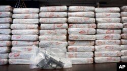 FILE - A firearm and 154 pounds of heroin worth at least $50 million are displayed by the Drug Enforcement Administration in New York, May 19, 2015. An annual DEA survey released Nov. 4, 2015, says heroin and drug overdoses have reached epidemic levels in the U.S.