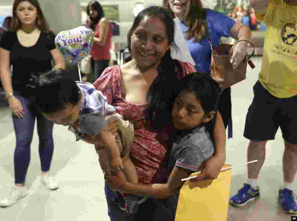 Buena Ventura Martin-Godinez, center, holds her son Pedro, left, as she is reunited with her daughter Janne, right, at Miami International Airport, July 1, 2018, in Miami, Florida. Martin crossed the border into the United States from Mexico in May with her son, fleeing violence in Guatemala. Her husband crossed two weeks later with their 7-year-old daughter Janne. All were caught by the Border Patrol, and were separated. Her daughter was released from a child welfare agency in Michigan.