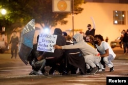 People huddle as they are struck by pepper-balls fired by police during a protest against the deaths of Breonna Taylor by Louisville police and George Floyd by Minneapolis police, in Louisville, Kentucky, U.S. May 29, 2020. (REUTERS/Bryan Woolston)