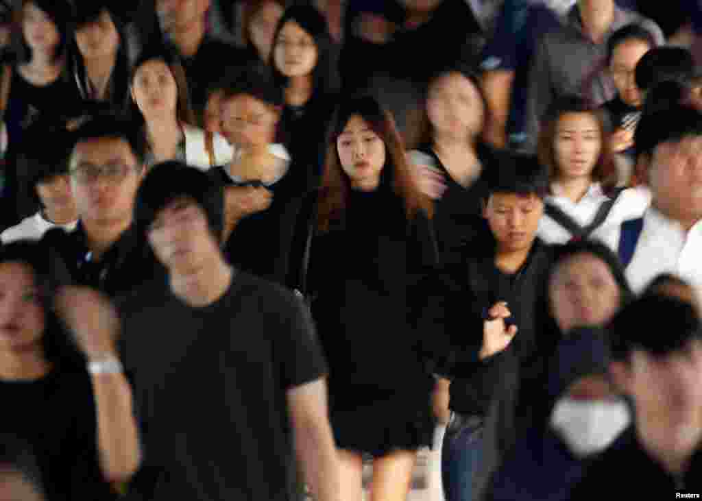 Passengers dressed in black and white or dark coloured clothes, to mourn the passing of Thailand's King Bhumibol Adulyadej, are seen during the morning rush hour at a station in Bangkok.