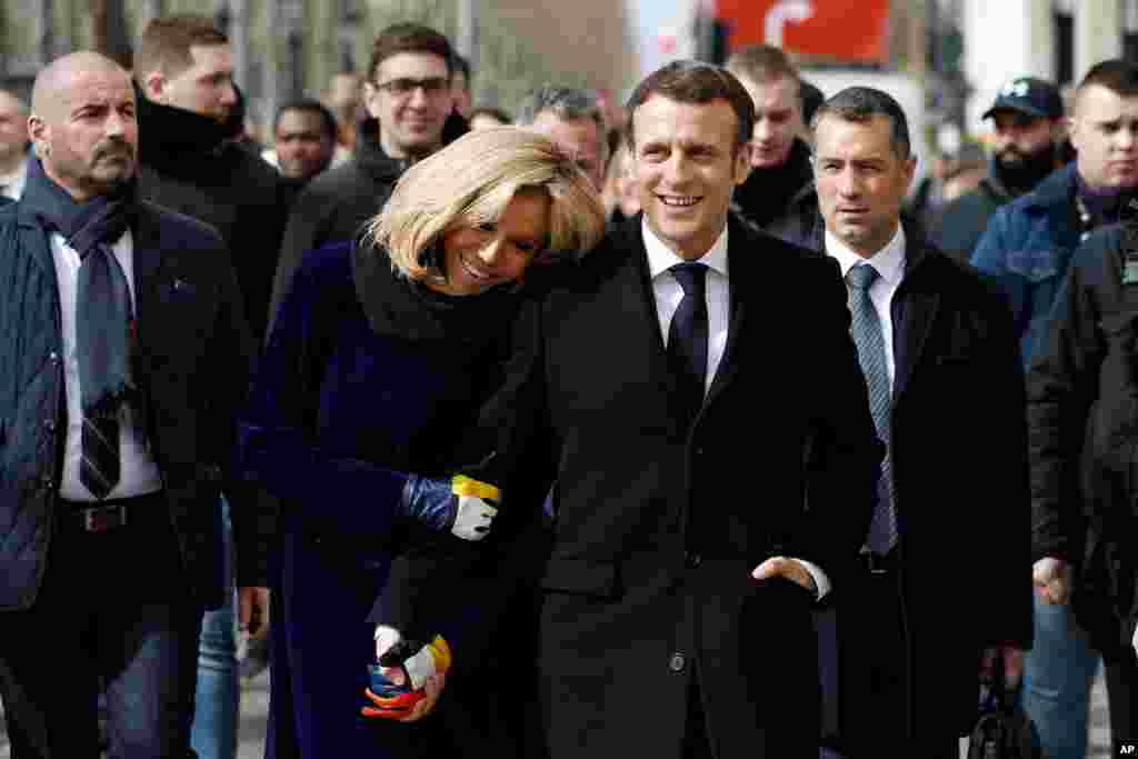 French President Emmanuel Macron and his wife Brigitte walk down the Champs-Elysees avenue after the opening of the Cafe Joyeux coffee shop, in Paris. The coffee shops is staffed by people with Down syndrome, autism and other cognitive disabilities.